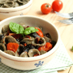 Orecchiette di grano arso con peperoni cruschi, olive e pomodorini: una ricetta vegana ispirata alla Basilicata, semplice e dal gusto deciso.