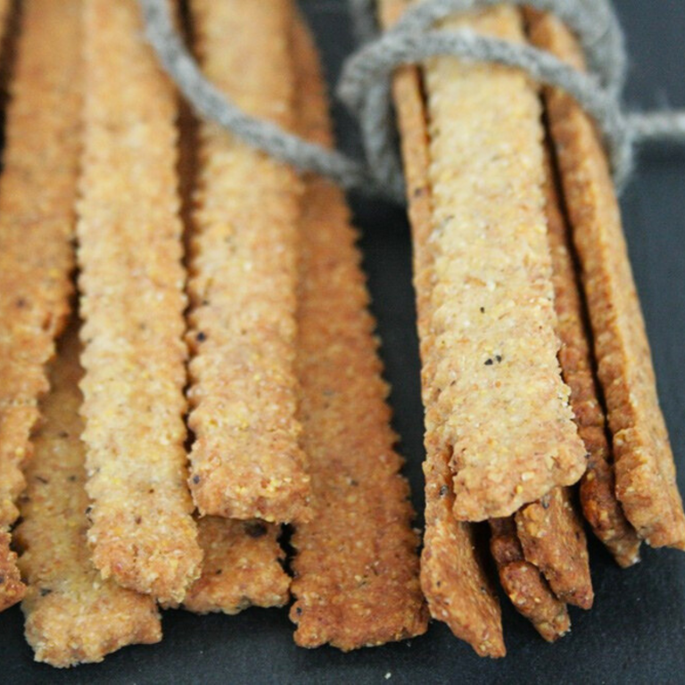 Grissini cacio e pepe vegani, croccanti e rustici, preparati con farine miste e formaggio vegetale alla frutta secca.
